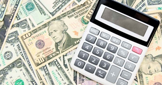 money on a table with a calculator on top