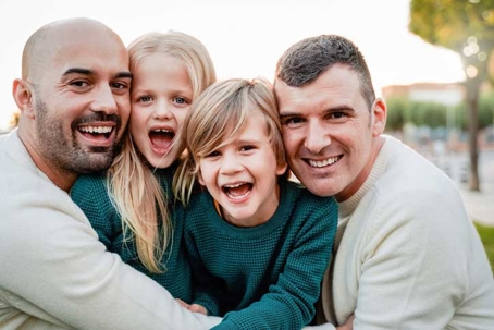 Gay male family having fun with children outdoors together in winter time - Lgbt community concept