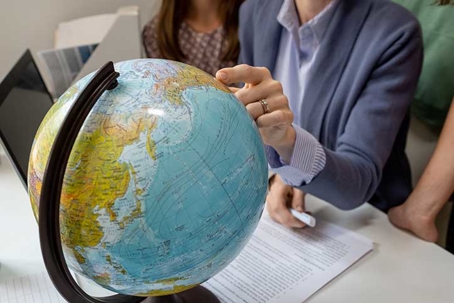 man's hand pointing at continent on globe