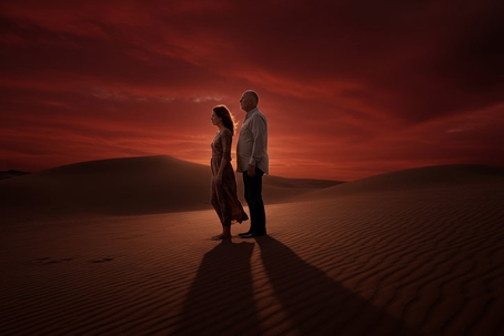 older couple standing on the sand dune during sunset