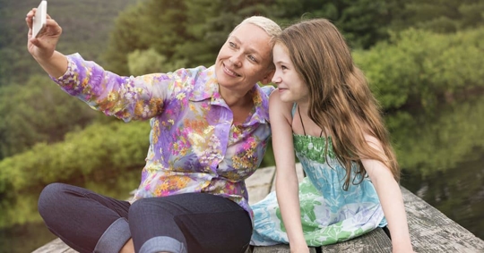 a woman and a child seated on a lake dock