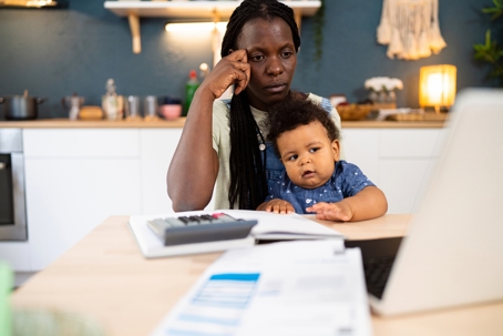 troubled mother budgeting money with child on her lap