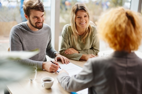 young couple signing documents with a professional