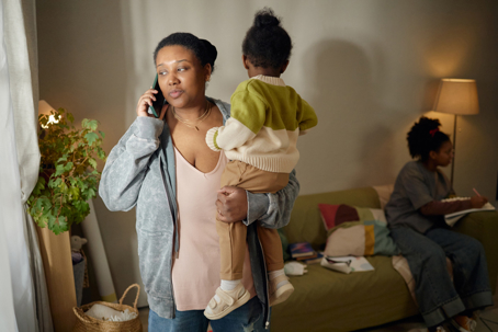 stressed mother on the phone while carrying child