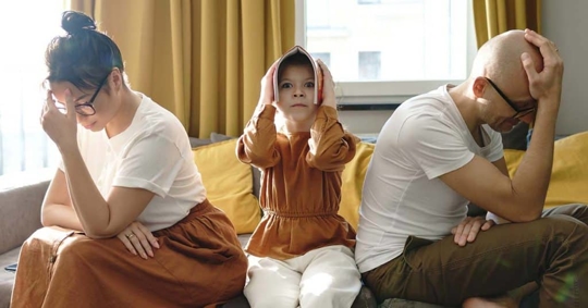 parents arguing with a child sitting in the middle of them