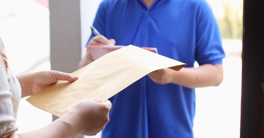 man in blue shirt signing for a packet a woman is holding