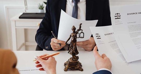 People reviewing divorce documents, a statue of justice, and legal papers.