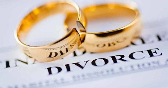 Two gold wedding rings rest on a document that says "DIVORCE".