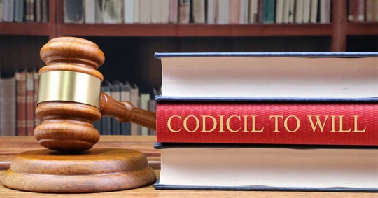 A wooden gavel rests on books titled "Codicil to Will".