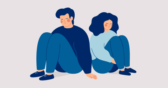 Two people sitting on the floor, looking down, appear sad.